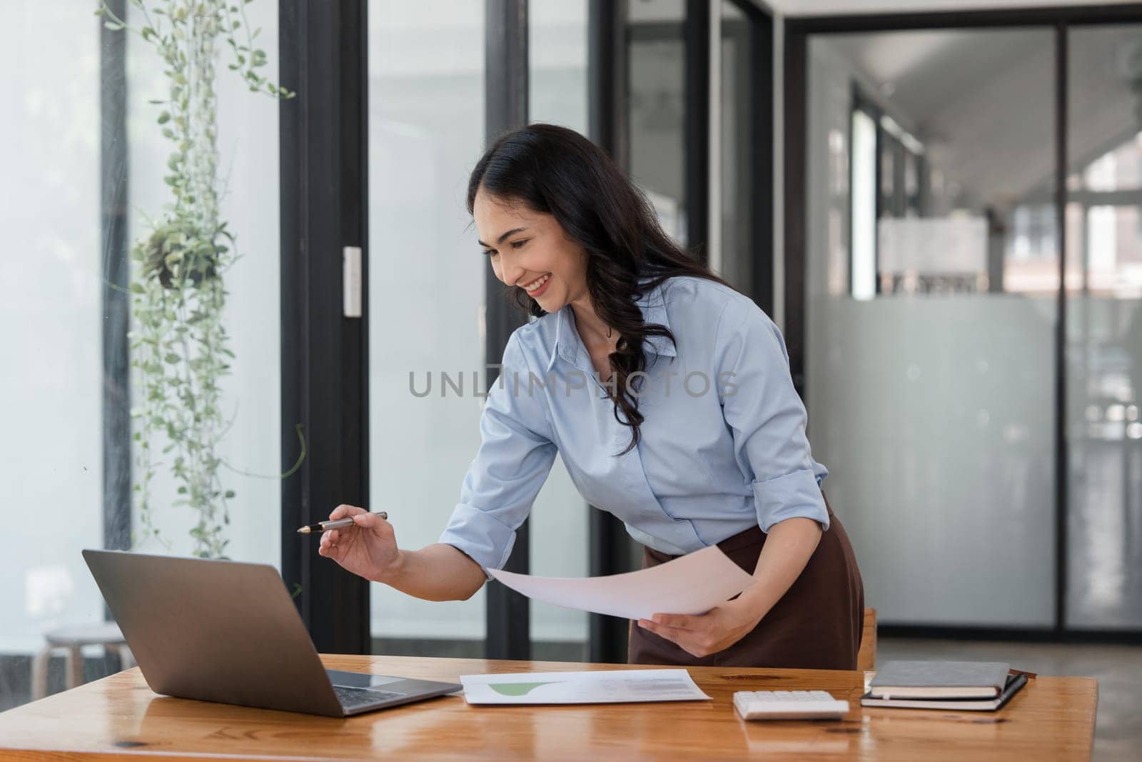 Asian businesswoman working for financial graphs showing results about their investments, planning successful business growth process by laptop computer.