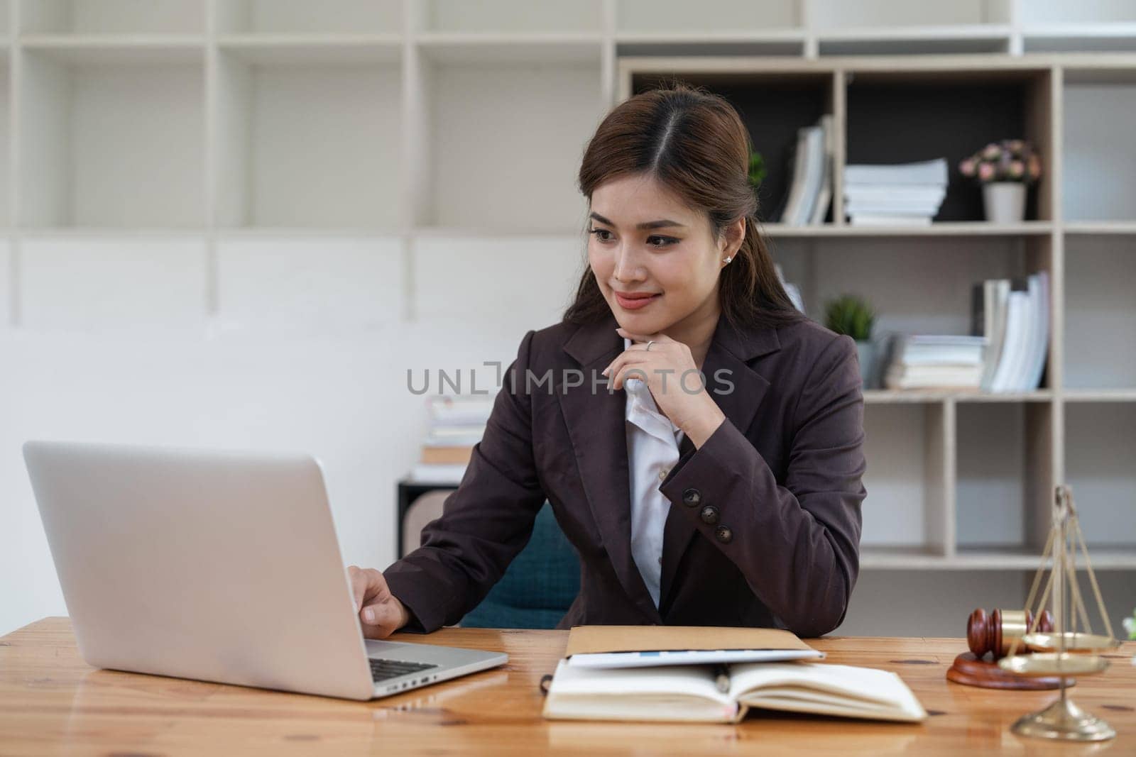 Attractive young lawyer in office Business woman and lawyers with brass scale on wooden desk in office. Law, legal services, advice, Justice and real estate concept.