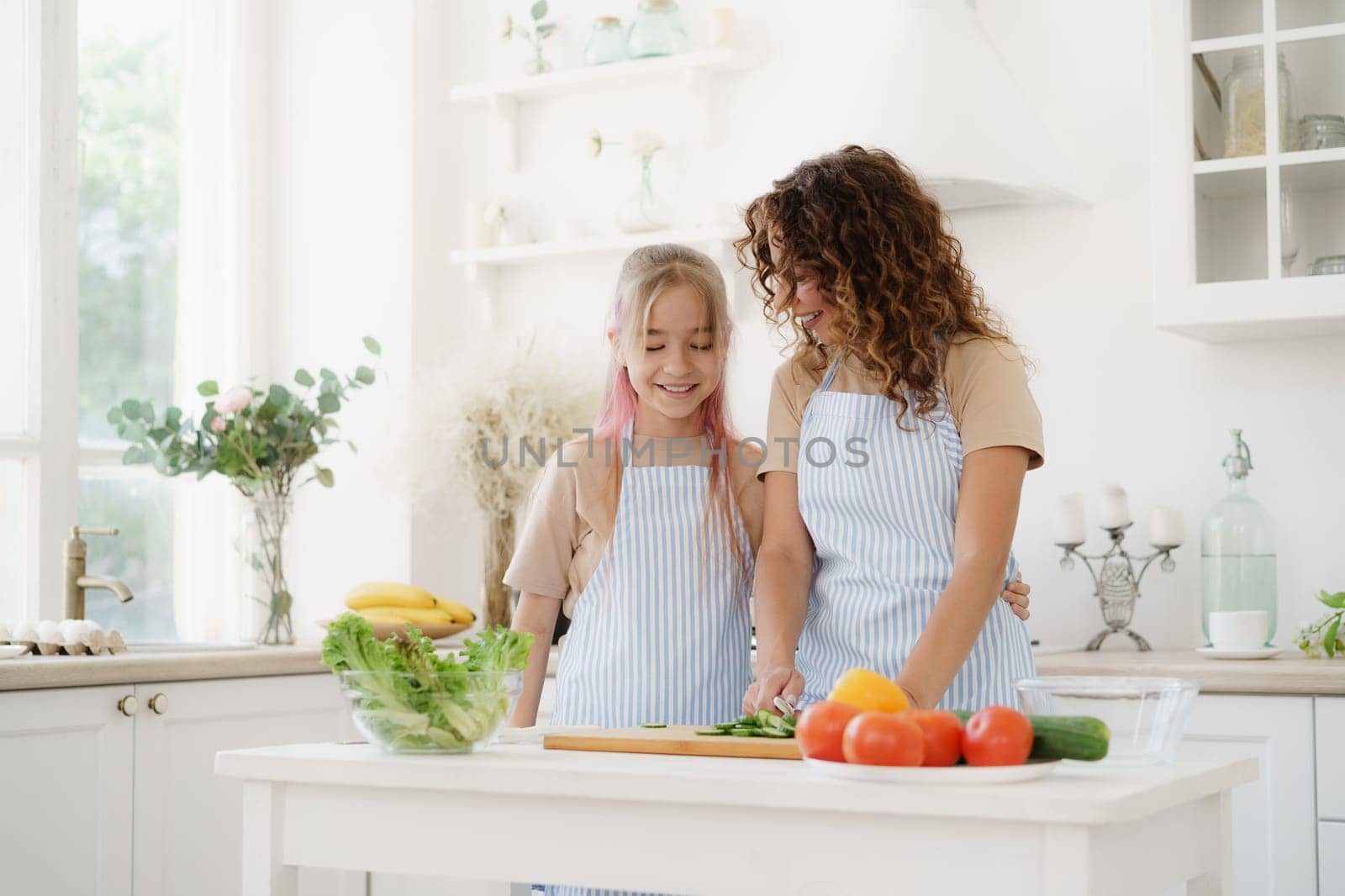 Mother and teen daughter preparing vegetable salad at kitchen, close up