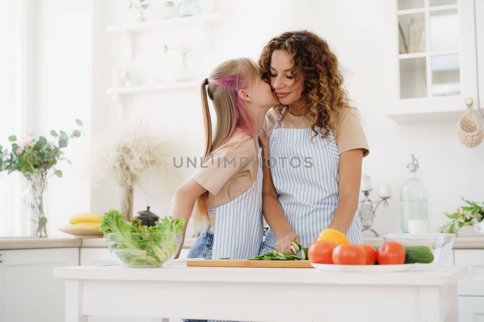 Mother and teen daughter preparing vegetable salad at kitchen by Fabrikasimf
