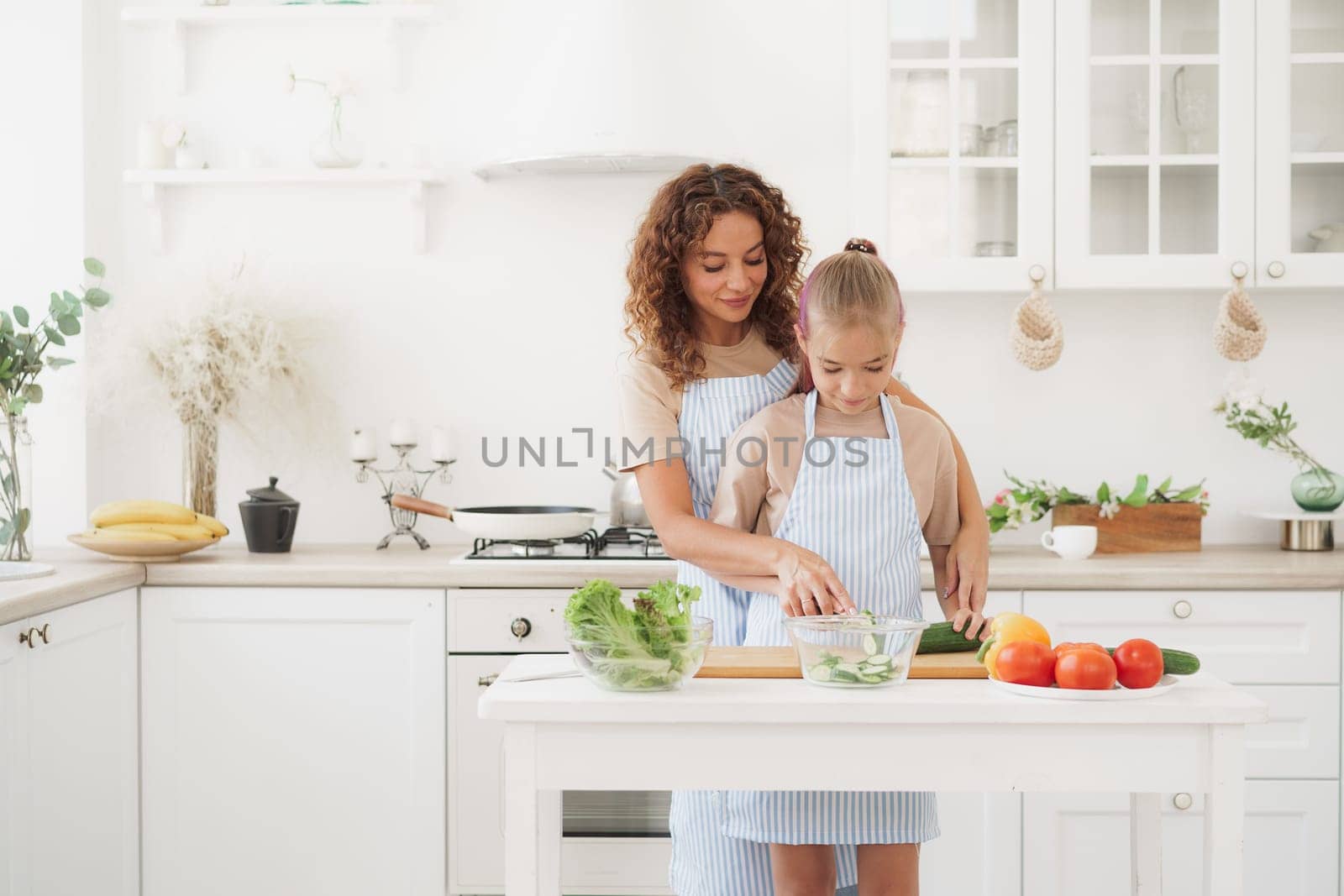 Mother and teen daughter preparing vegetable salad at kitchen by Fabrikasimf