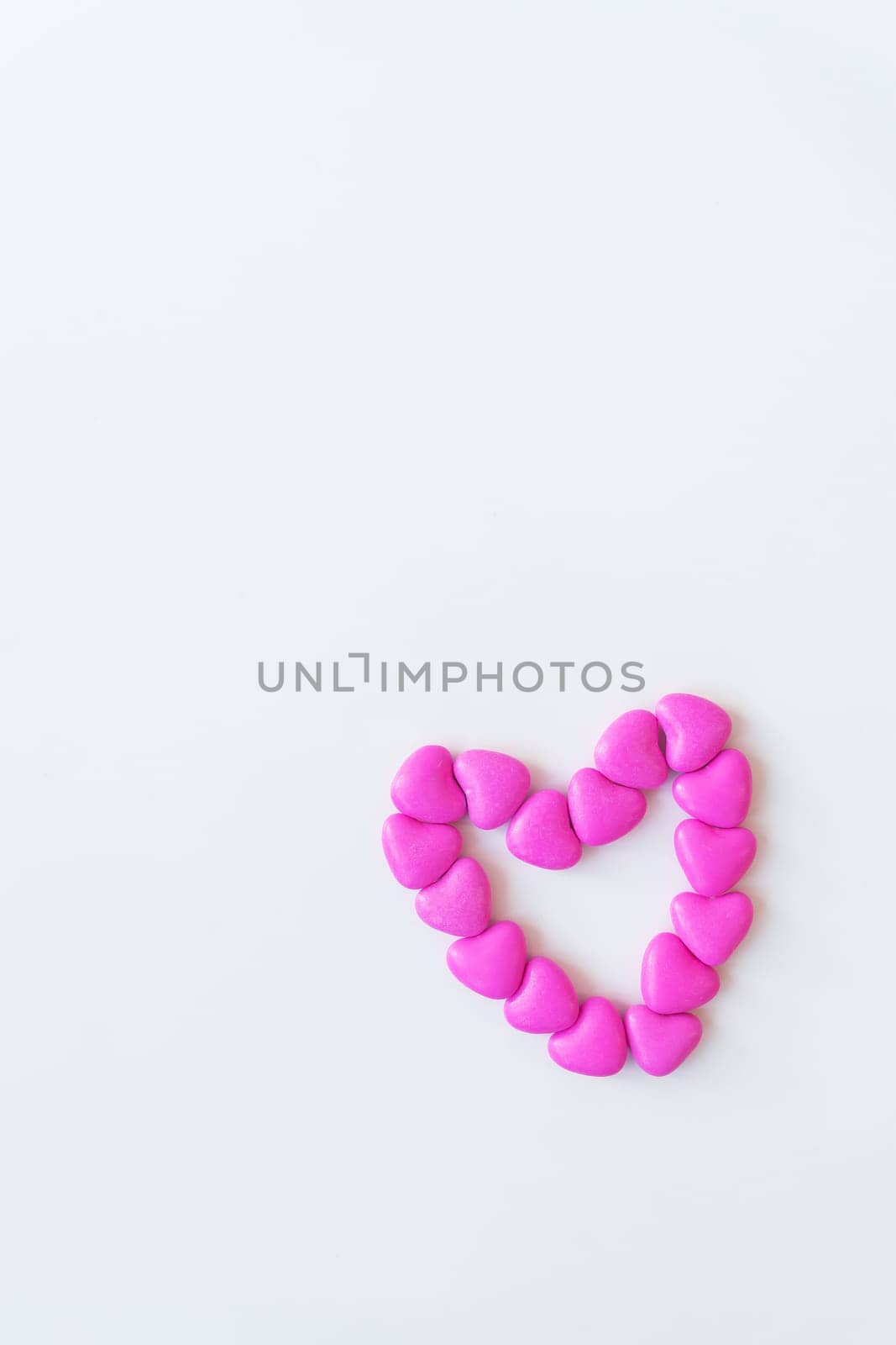 Valentine's day pattern background flat lay top view of heart shaped pink candies scattered on white background. by sfinks