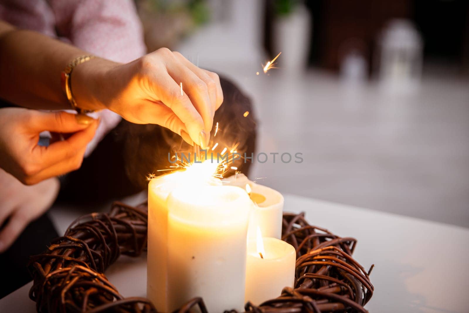 A girl from the fire of a candle standing on a table lights fireworks. by fotodrobik