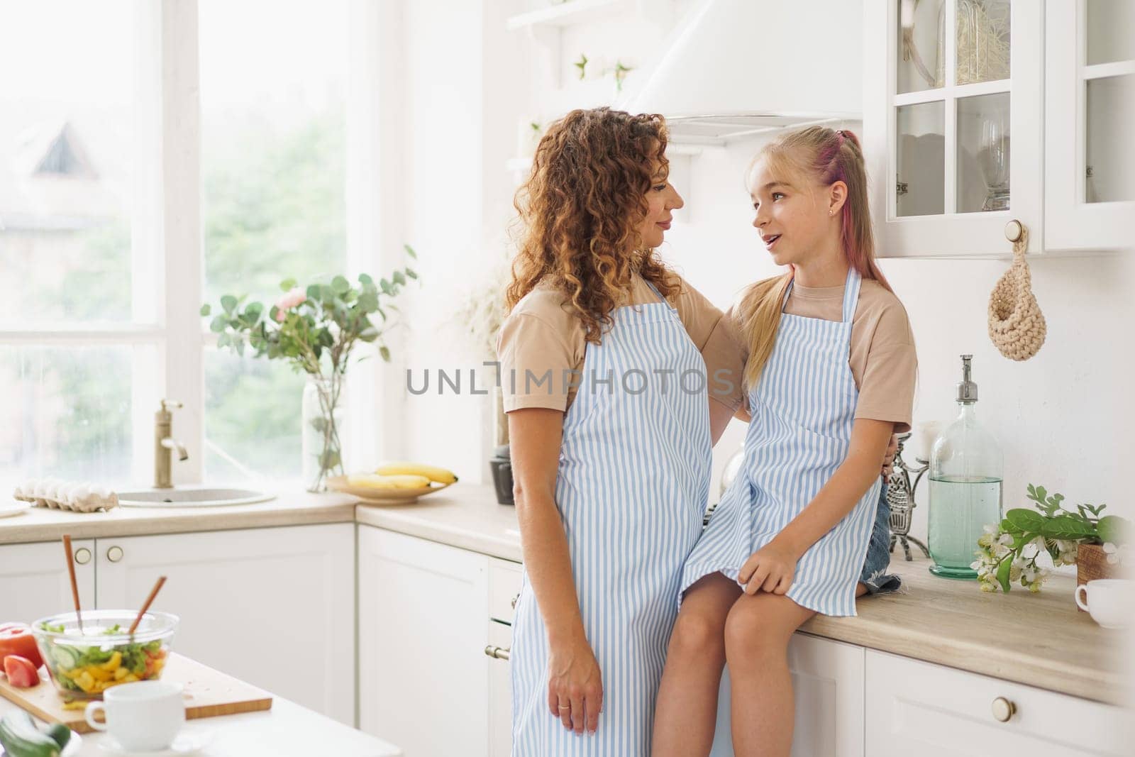 Portrait of a teen girl with her mother at home in kitchen, close up