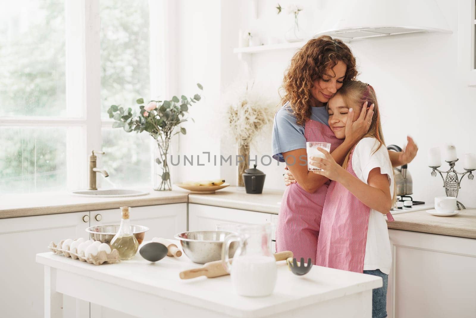 Portrait of a teen girl with her mother at home in kitchen, close up