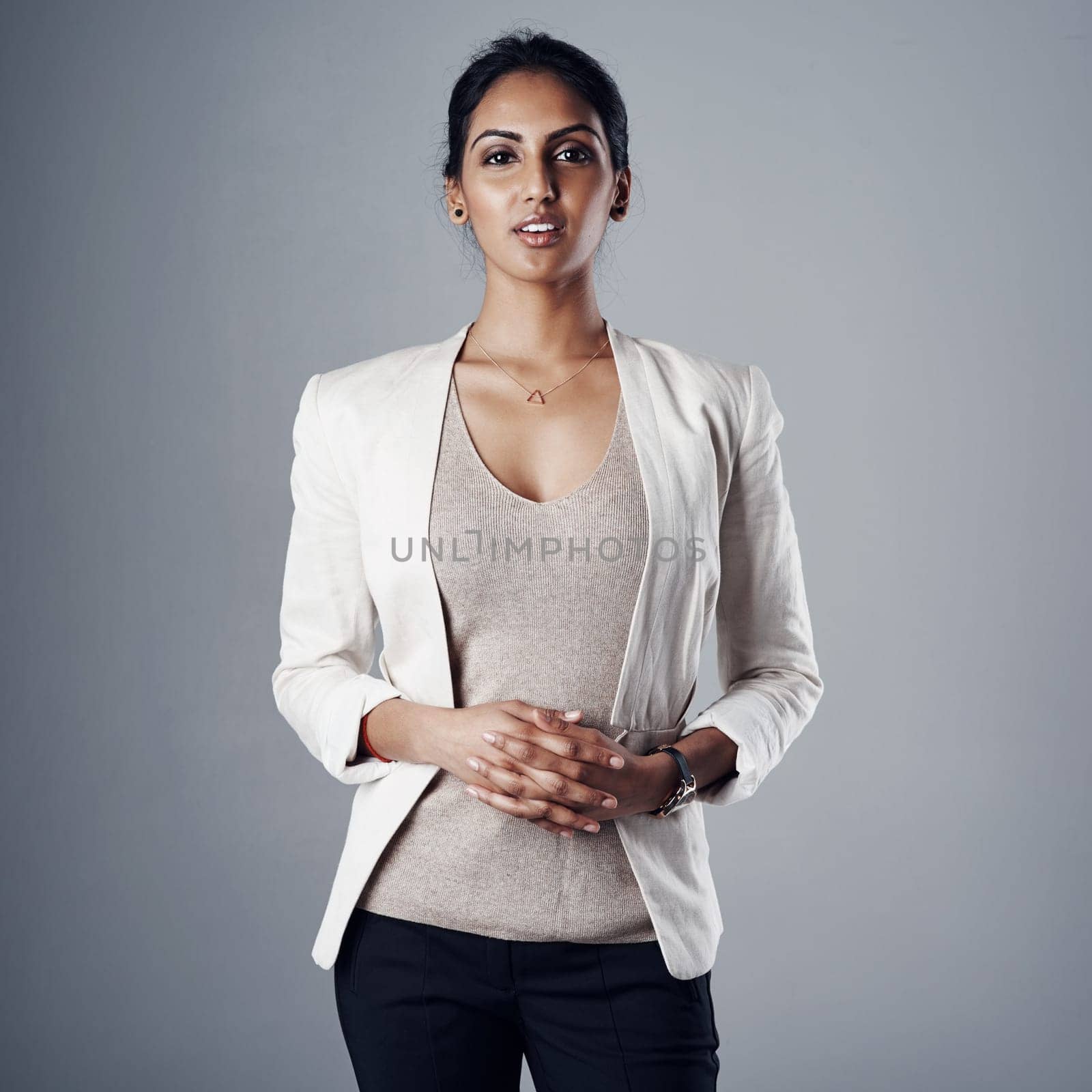 Staying firm in what I stand for. Studio portrait of a young businesswoman posing against a gray background. by YuriArcurs