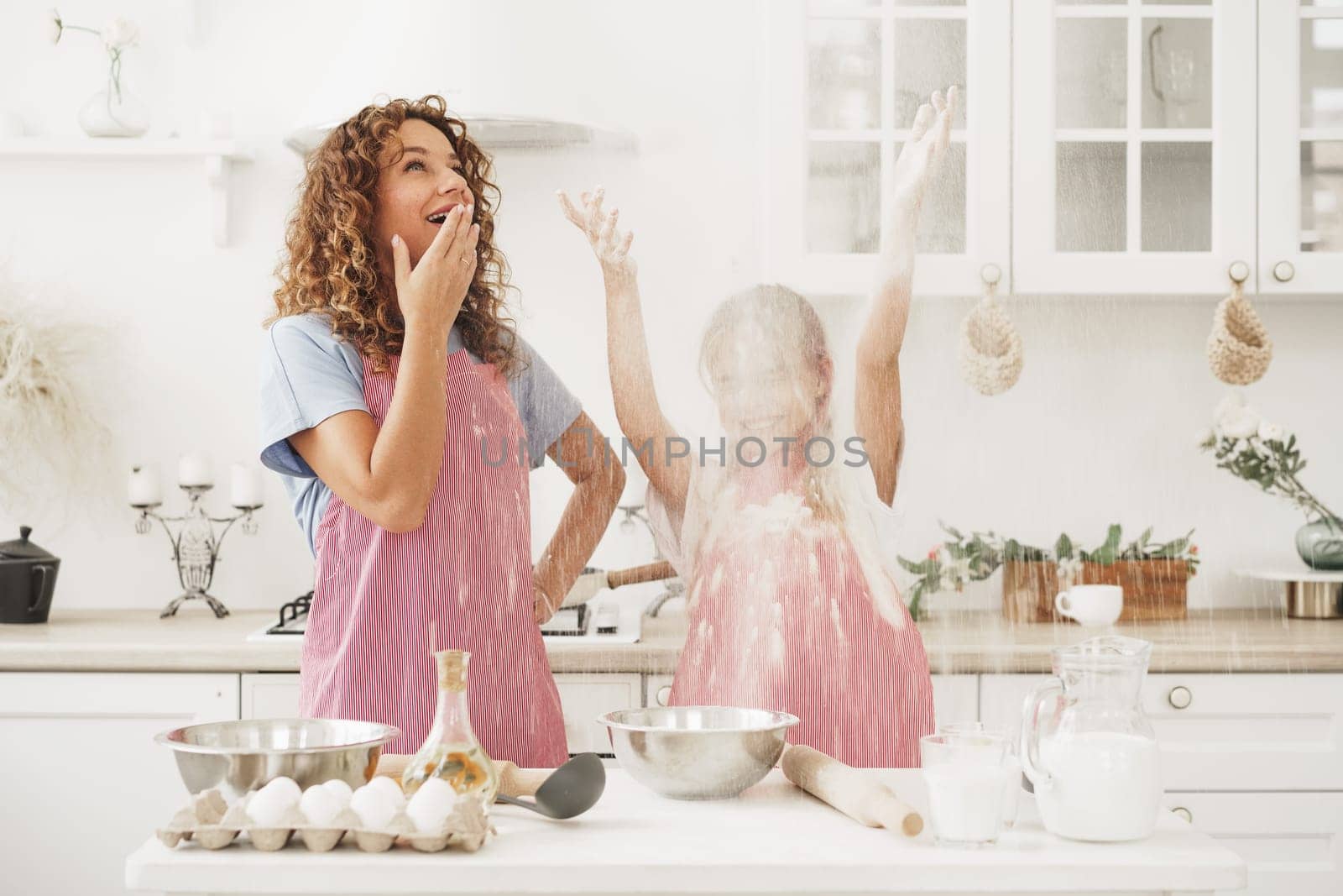 Mother and daughter having fun while cooking dough in kitchen, close up