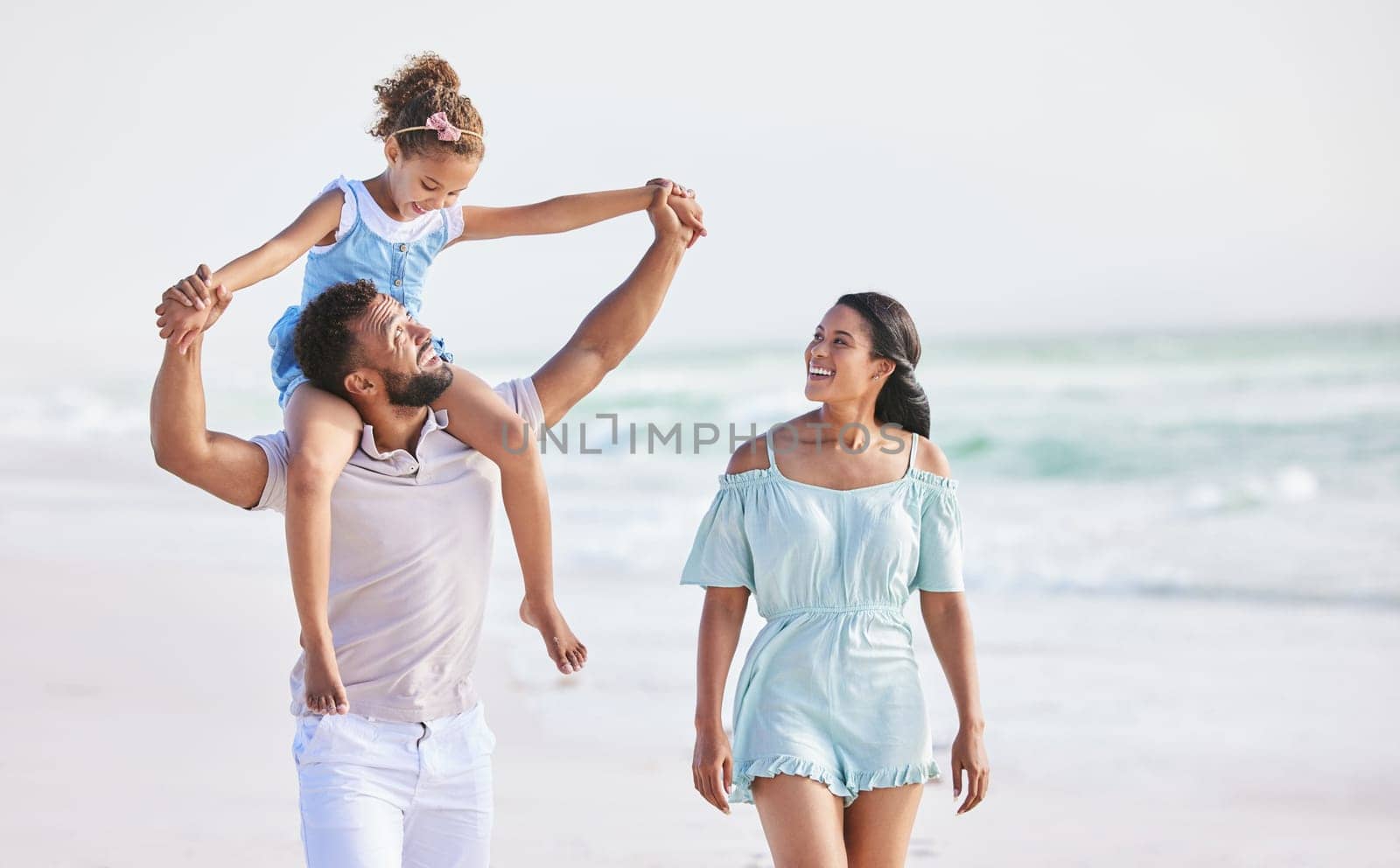 Holding hands, beach or parents walking with a happy kid for a holiday vacation together with happiness. Piggyback, mother and father playing or enjoying family time with a young boy or kid in summer by YuriArcurs