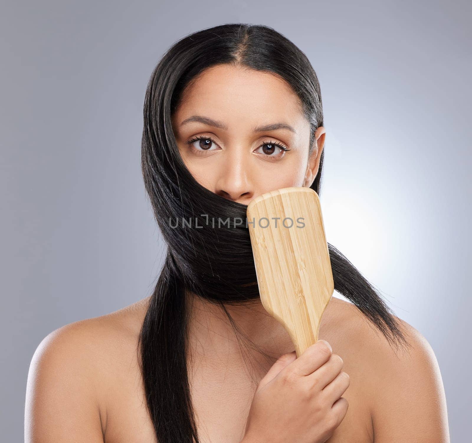 Woman, portrait and brush in studio for hair grooming, salon or style against a grey background. Female person, young model and clean beauty for brushing, haircare treatment and smooth texture.
