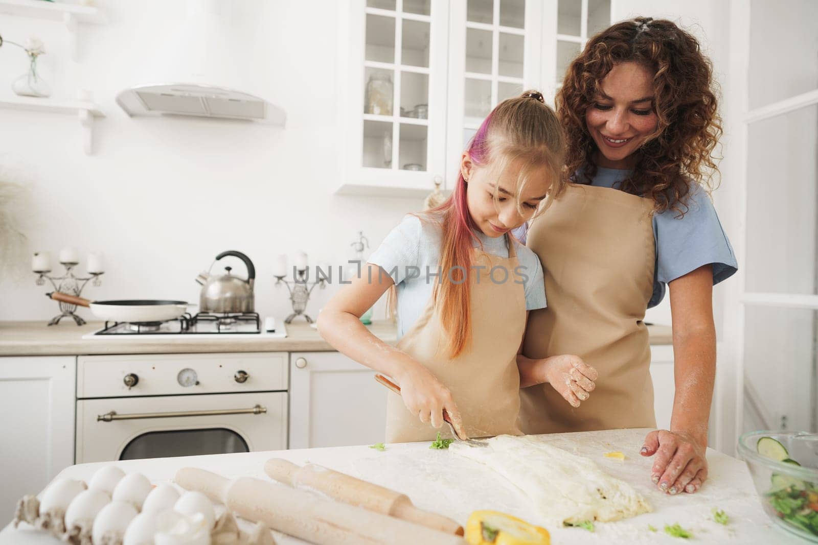 Mother and daughter having fun while cooking dough in kitchen, close up