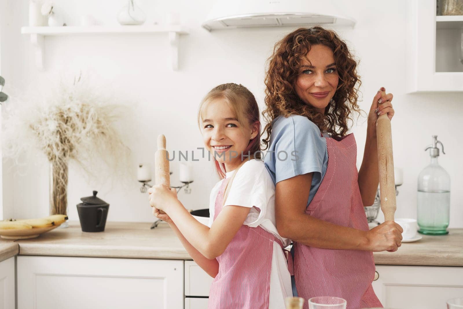 Portrait of a teen girl with her mother at home in kitchen, close up