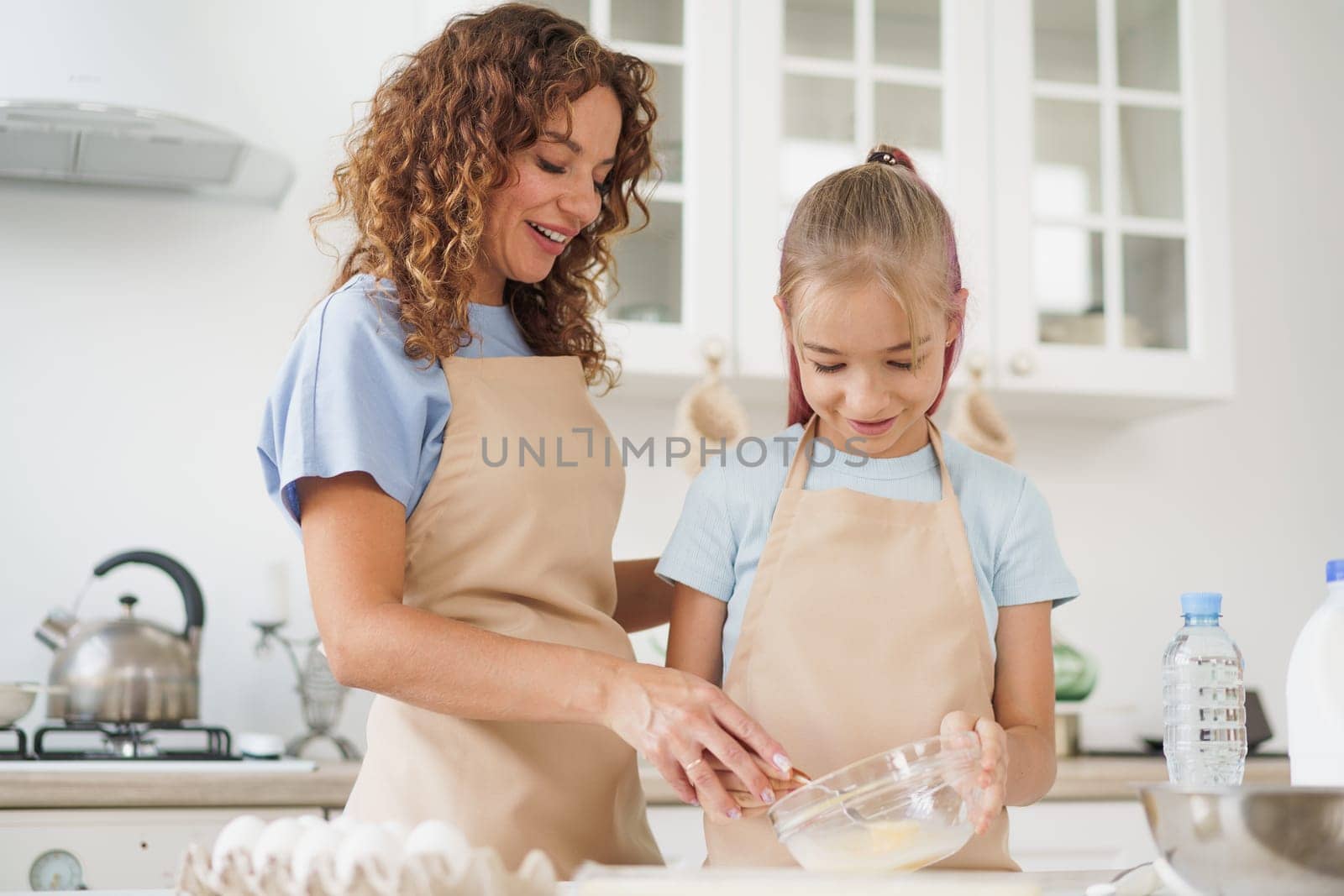 Mother and teen daughter making dough for pastry toghether in kitchen, close up