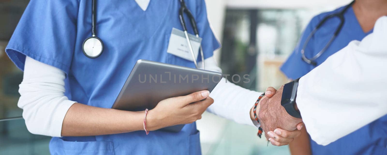 Heres to finding a cure together. an unrecognizable nurse standing and shaking a doctors hand in the clinic. by YuriArcurs