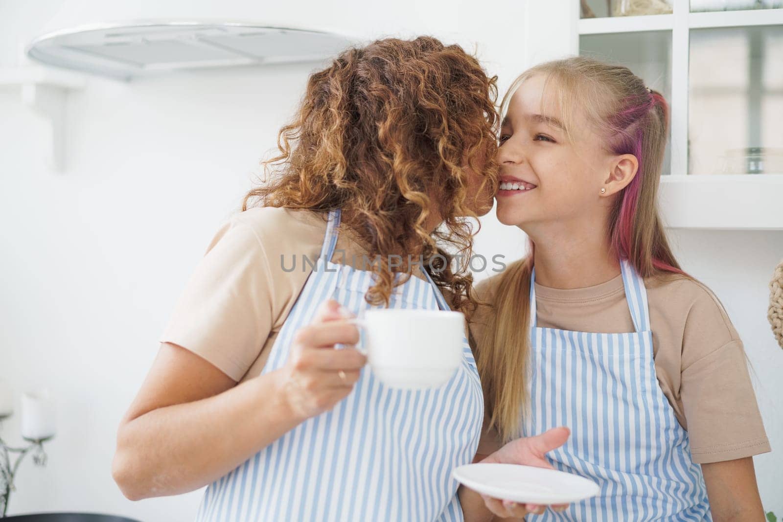 Portrait of a teen girl with her mother at home in kitchen, close up
