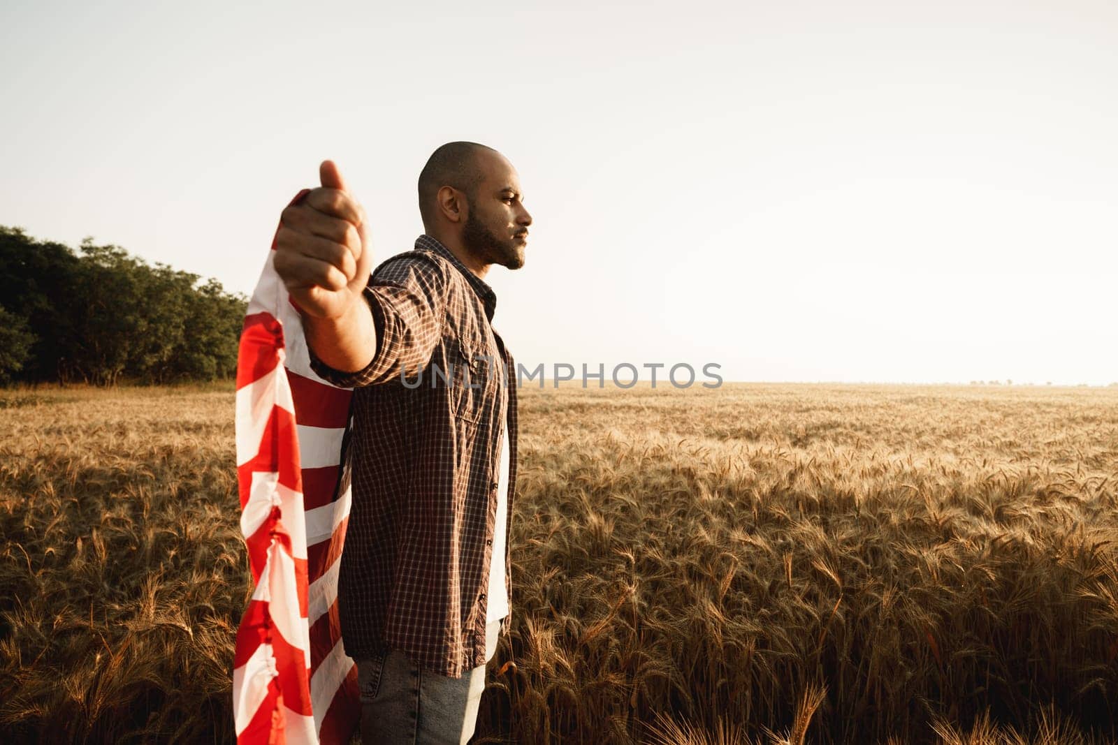 African american young man holding USA national flag through wheat field by Fabrikasimf