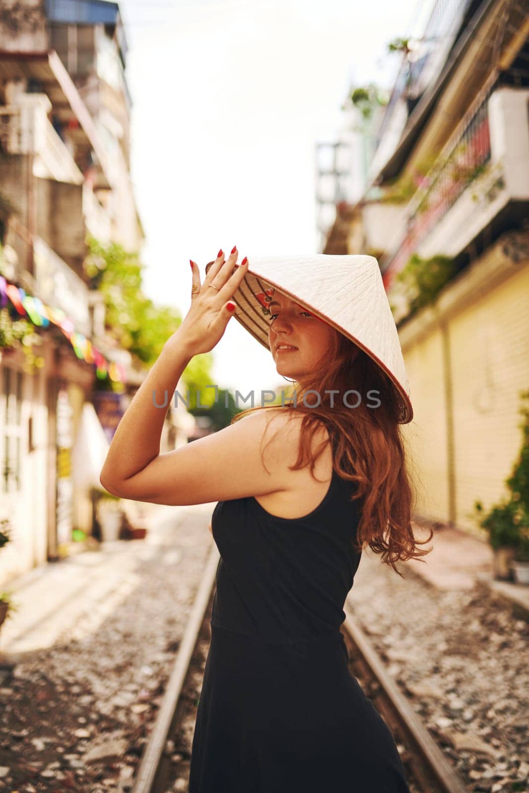 I use travel as an escape from daily life. a young woman wearing a conical hat while exploring a foreign city. by YuriArcurs