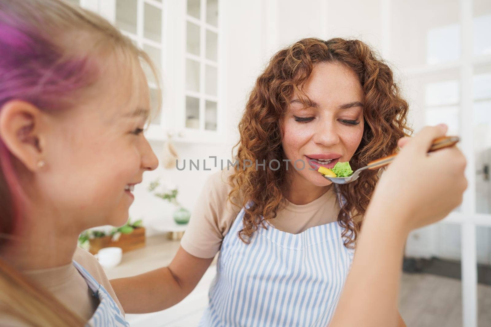 Portrait of a teen girl with her mother at home in kitchen, close up