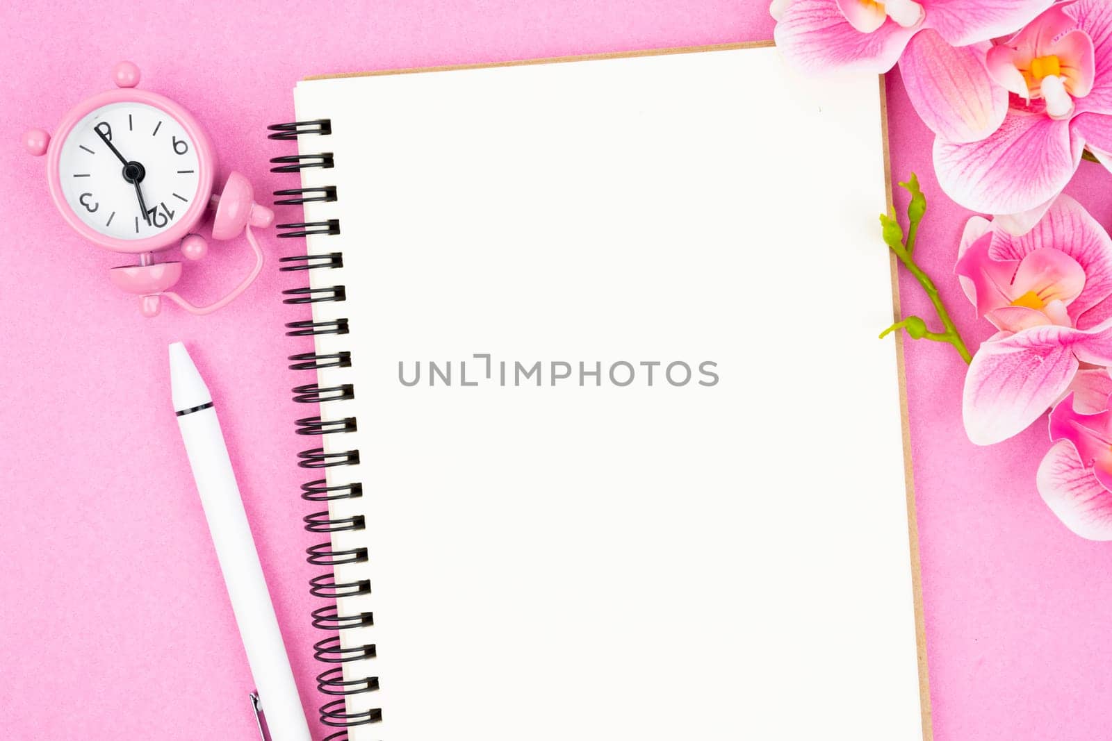 Blank open notebook and clock with pink color orchid for your text or message.