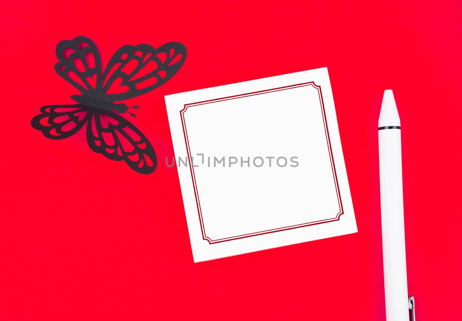 Blank reminder note paper and carve of paper butterfly with pen on red background, space for text.