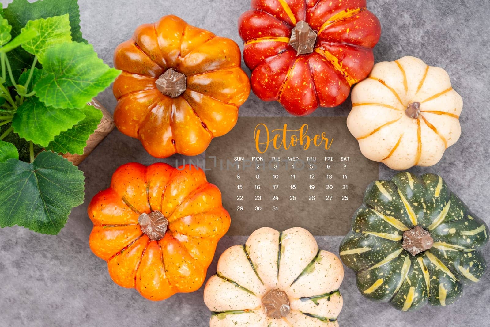 The October 2023 Calendar and pumpkins on black wood background. by Gamjai