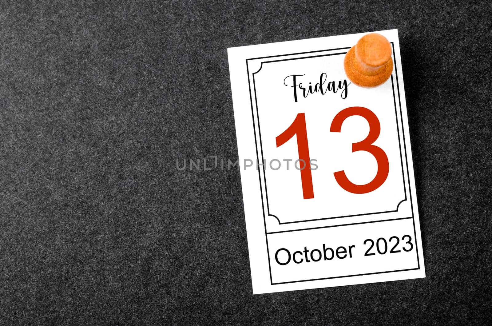 Friday the 13th calendar with wooden push pin on black background.