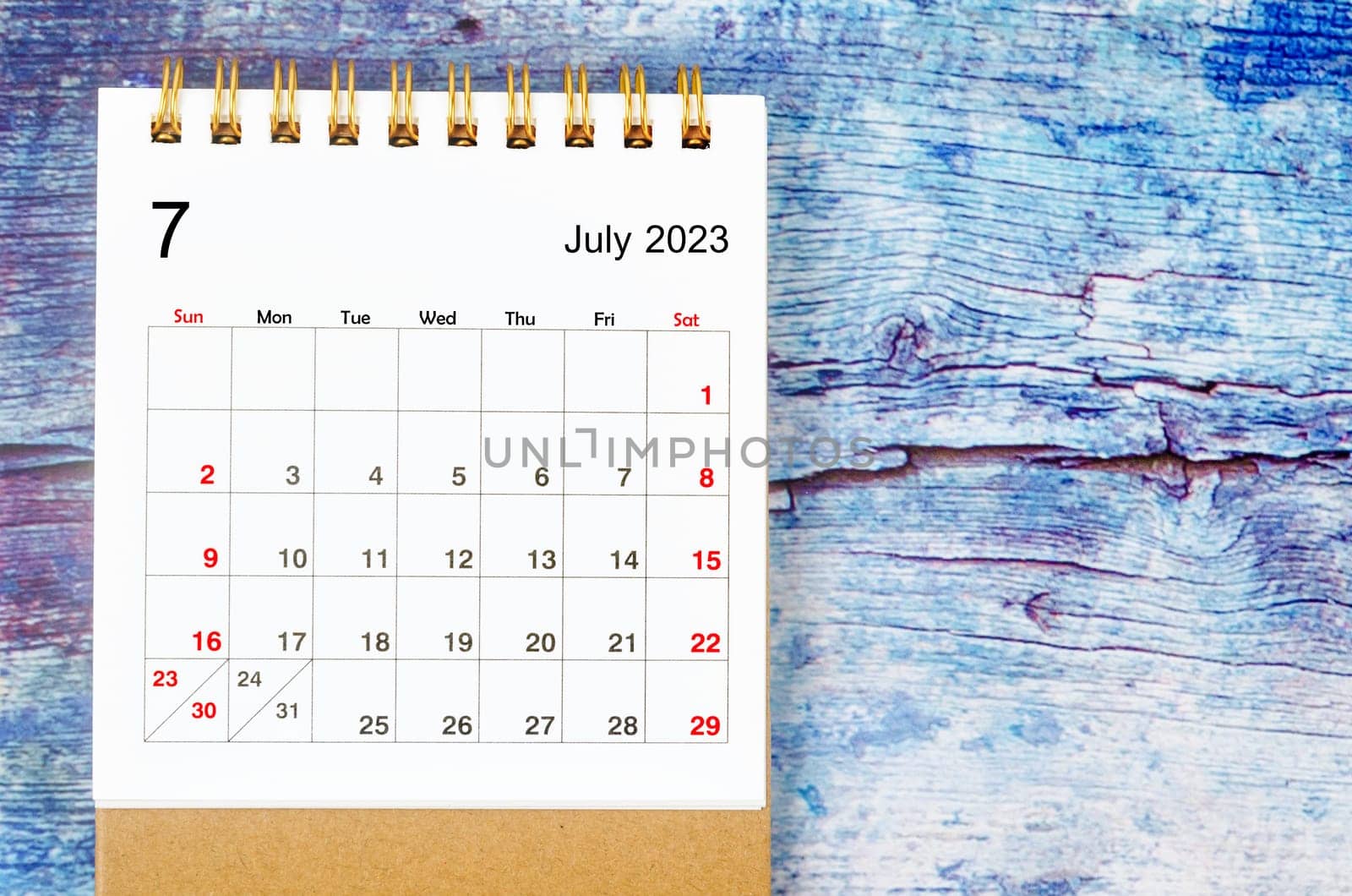 July 2023 Monthly desk calendar for 2023 year on old blue wooden background.
