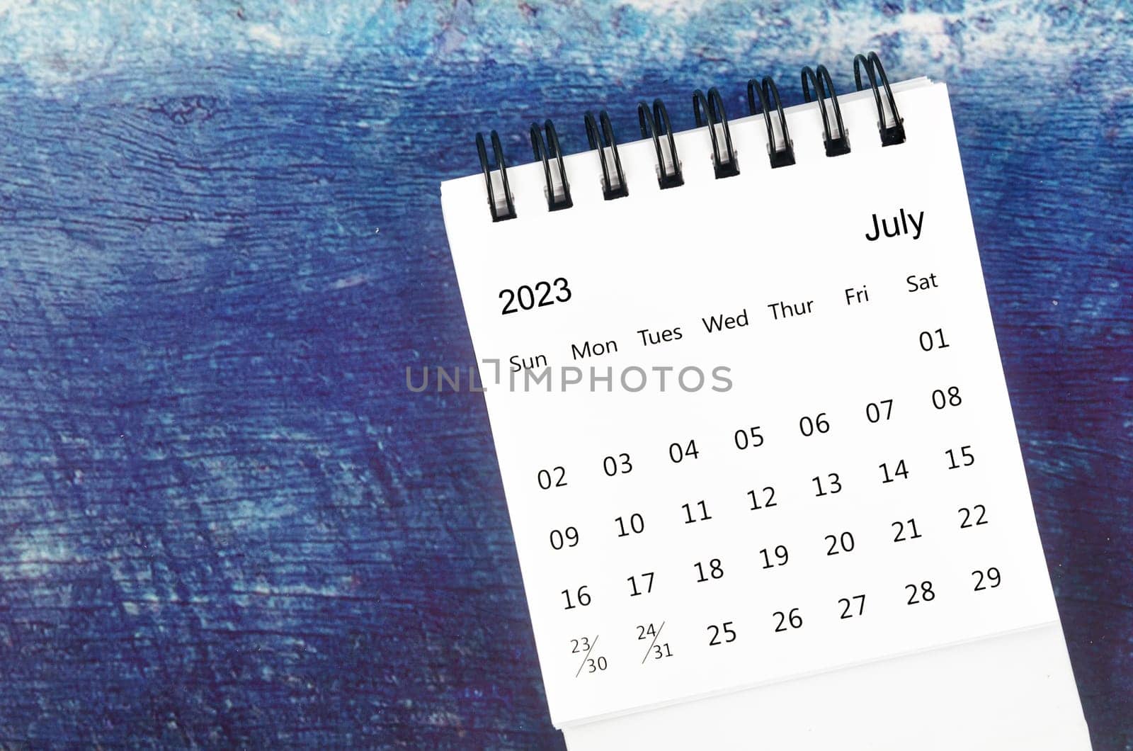 The July 2023 Monthly desk calendar for 2023 year on old blue wooden background. by Gamjai