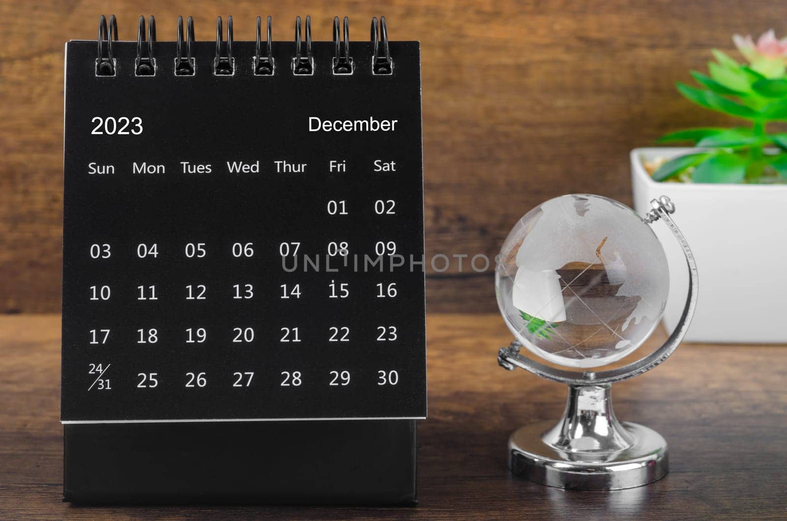 The December 2023 desk calendar for 2023 year Black color with a crystal globe against a wooden table background. by Gamjai