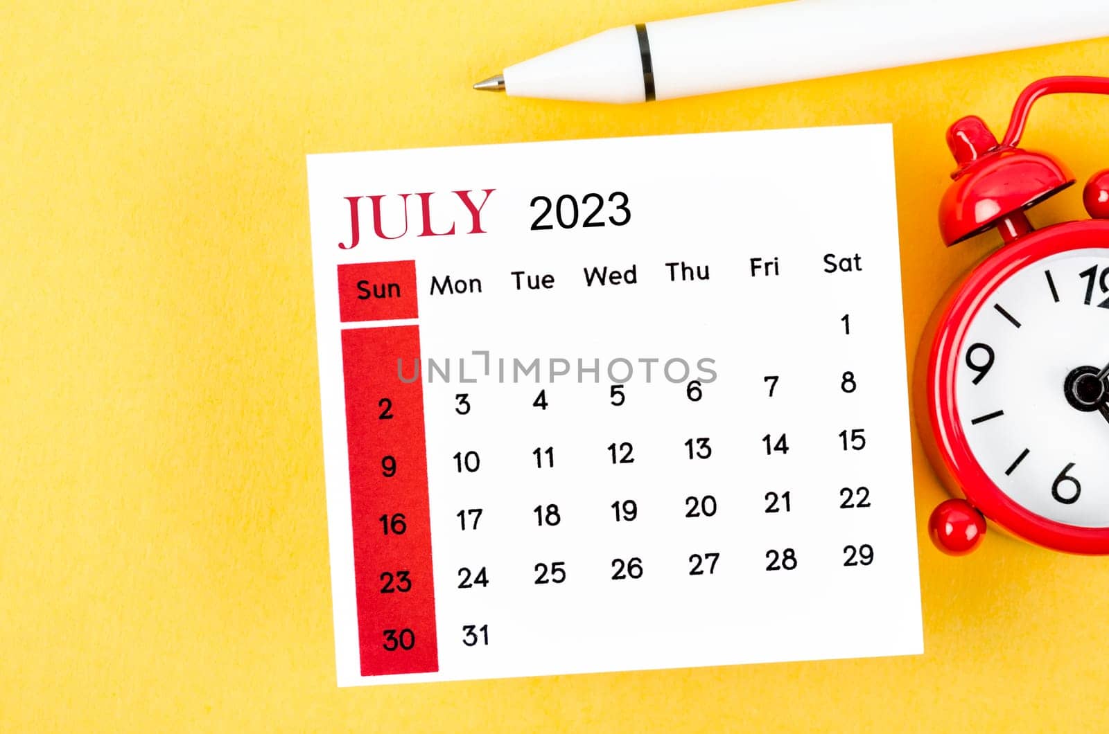 The July 2023 Monthly calendar for 2023 year with alarm clock on yellow background. by Gamjai