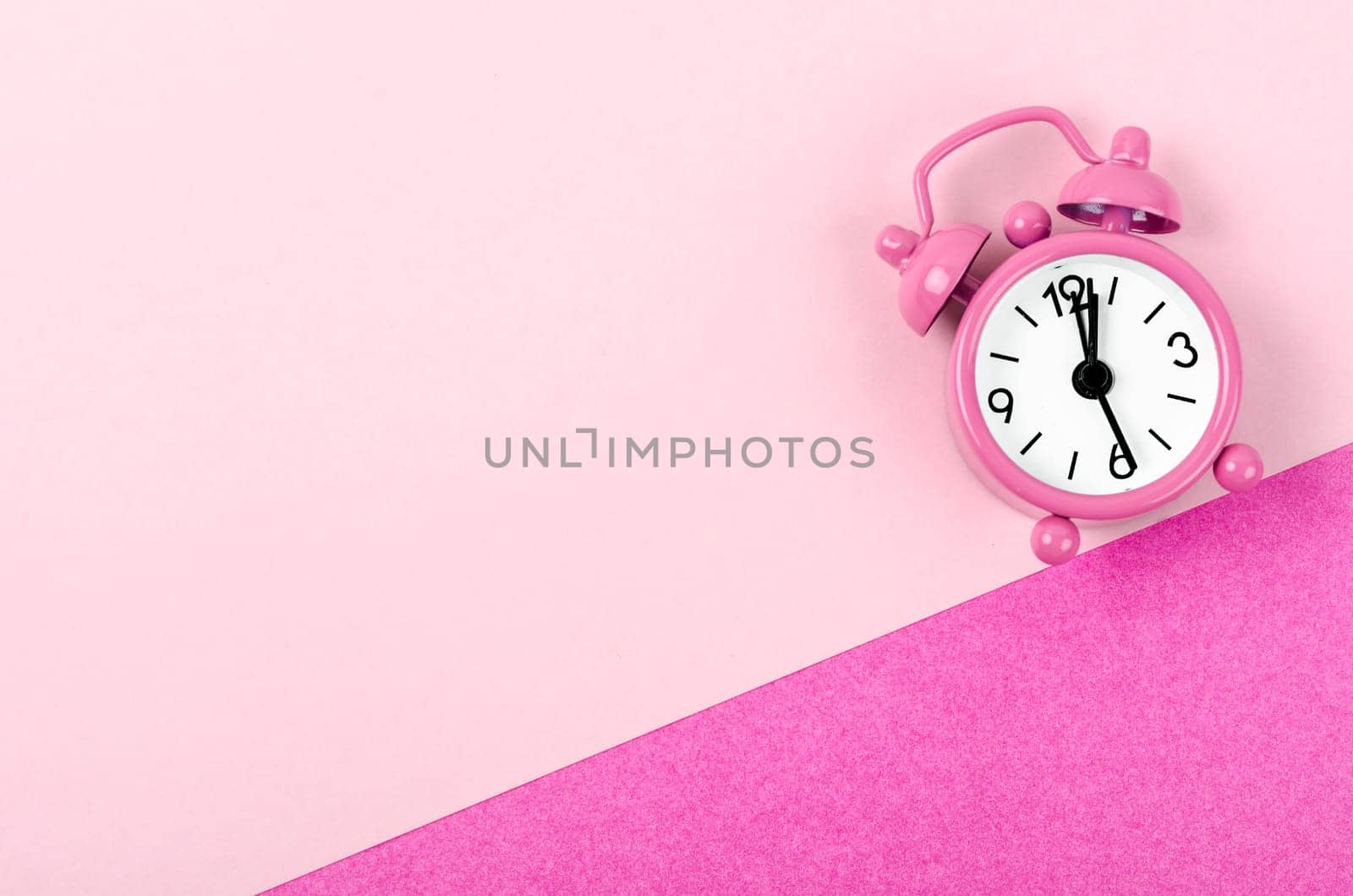 A Vintage pink color alarm clock on pink background. by Gamjai