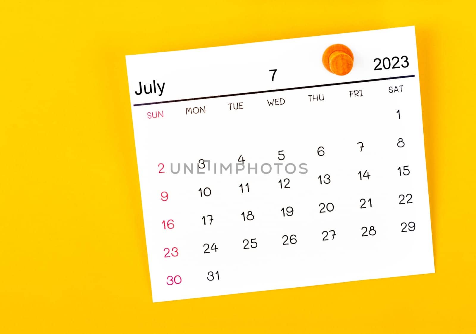 The July 2023 and wooden push pin on yellow background. by Gamjai