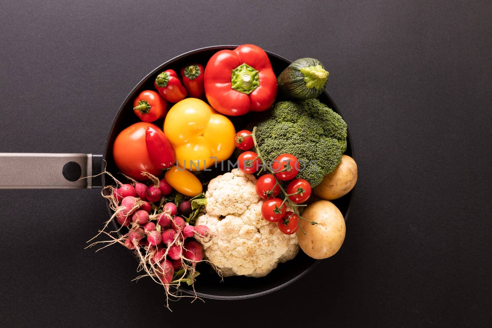 Directly above shot of various colorful vegetables in frying pan on black background by Wavebreakmedia