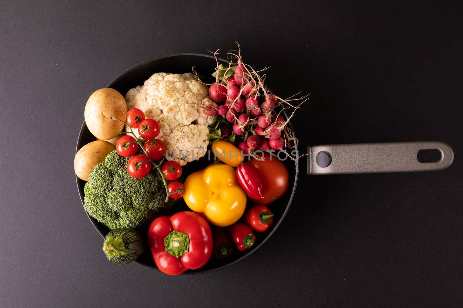 Overhead view of various colorful vegetables in frying pan on black background. unaltered, vegetable, healthy food, raw food, variation and organic concept.