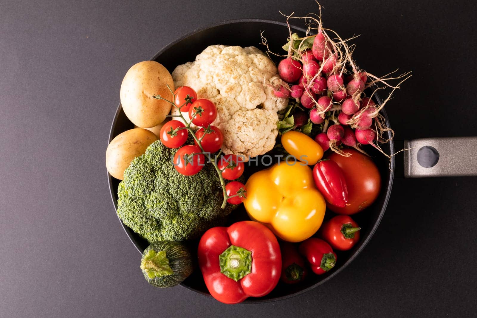 Overhead close-up of various colorful vegetables in frying pan on black background. unaltered, vegetable, healthy food, raw food, variation and organic concept.