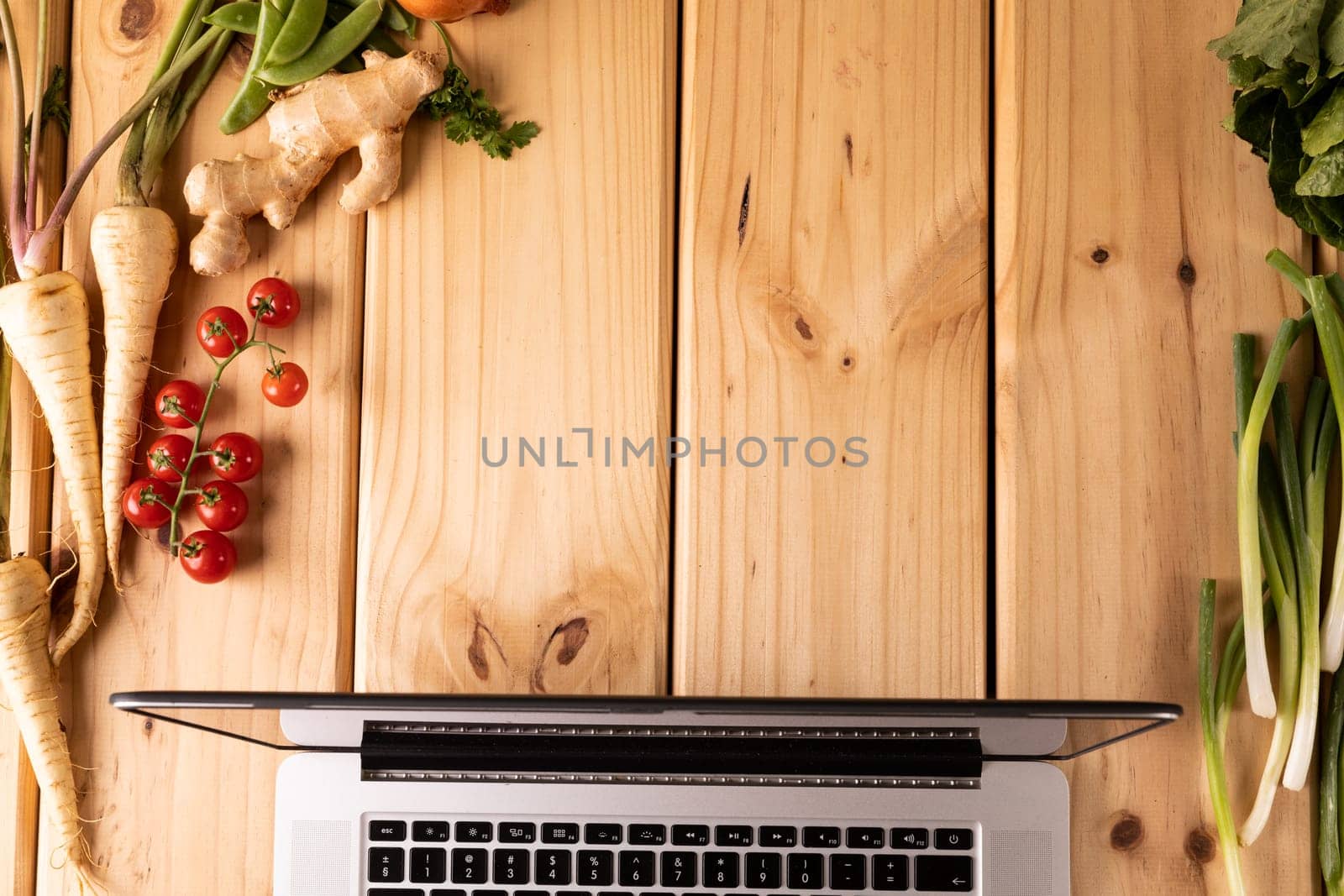 Directly above shot laptop by vegetables and spices on wooden table with empty space by Wavebreakmedia