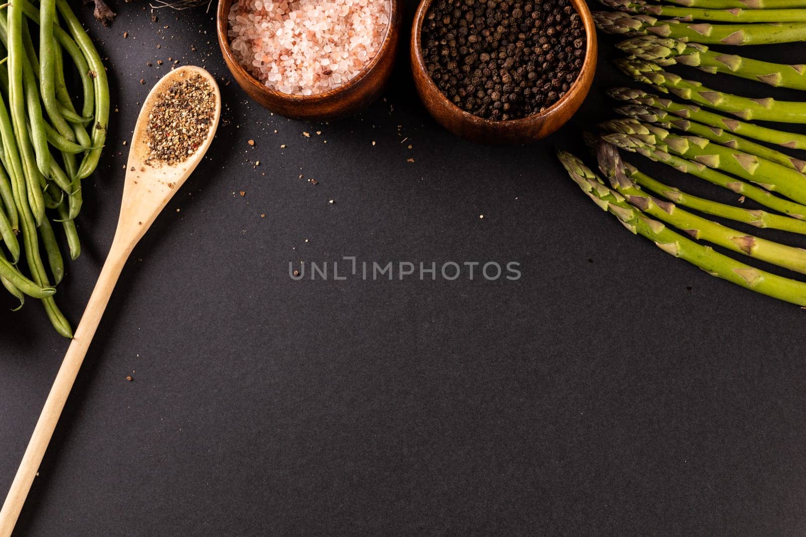 High angle view of spices with asparagus and french beans on black background with copy space by Wavebreakmedia