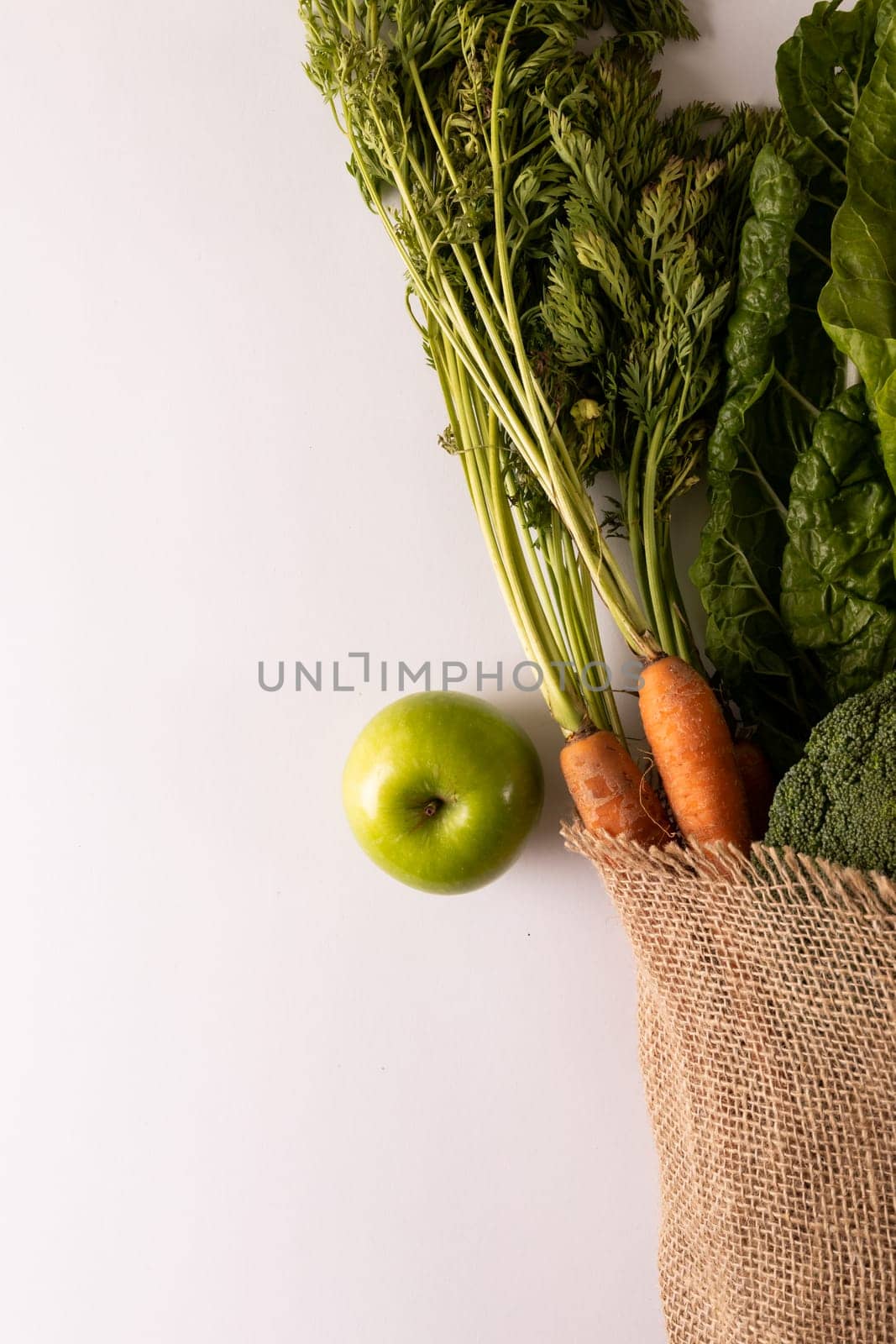 Overhead view of fresh vegetables and fruit with burlap on white background, copy space by Wavebreakmedia