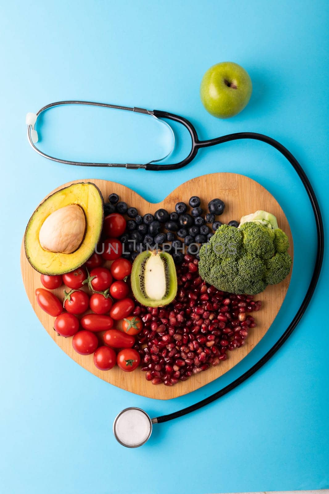 Directly above view of healthy food on heart shaped cutting board by stethoscope on blue background. unaltered, healthy eating, food, organic, healthcare, copy space.
