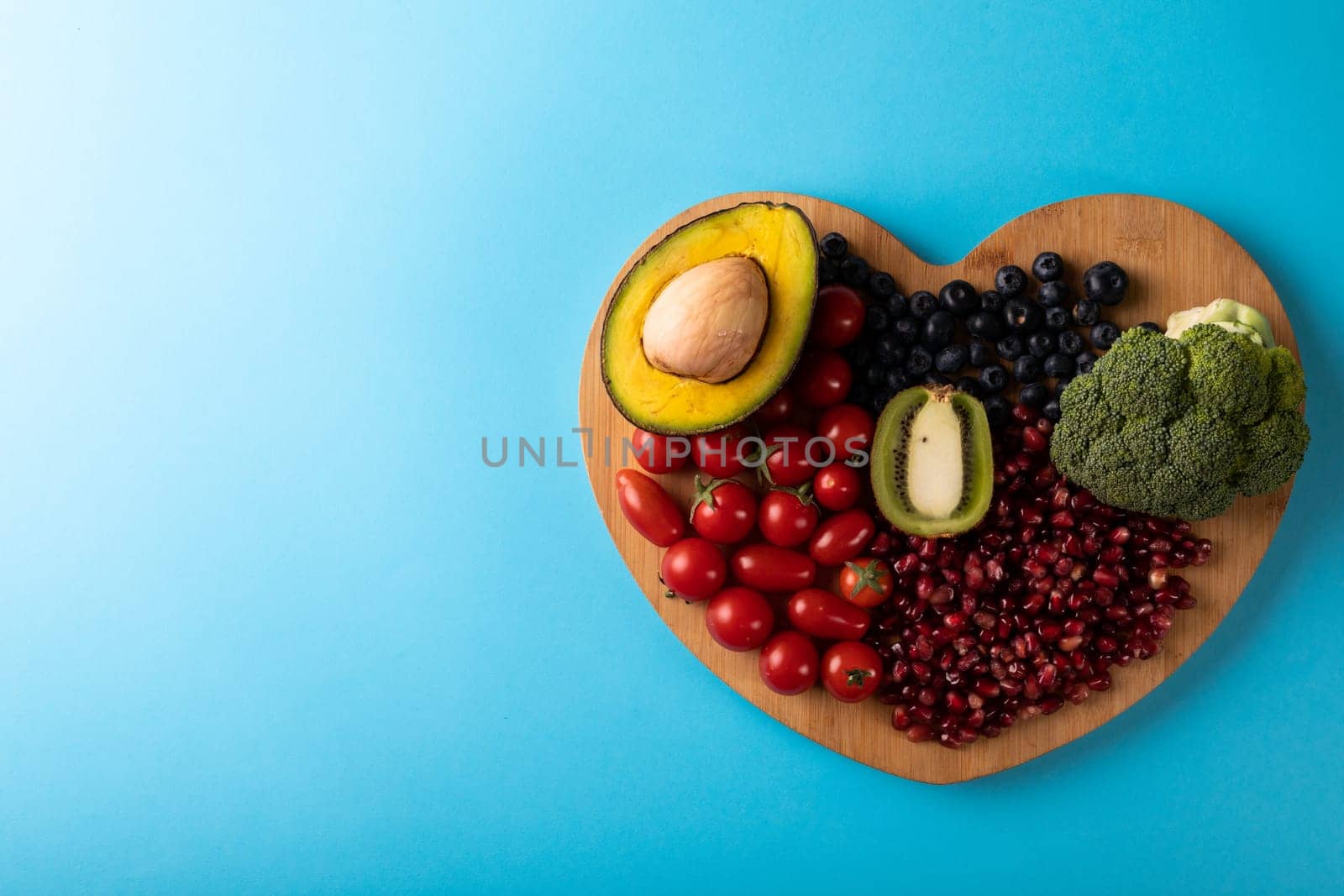 Directly above view of healthy food on heart shaped cutting board over blue background. unaltered, healthy eating, food, organic, copy space.