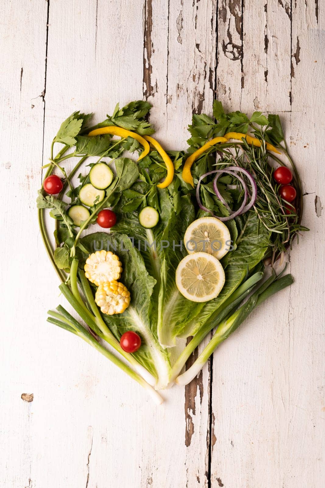 Overhead view of fresh green vegetables arranged as heart shape on white wooden table by Wavebreakmedia