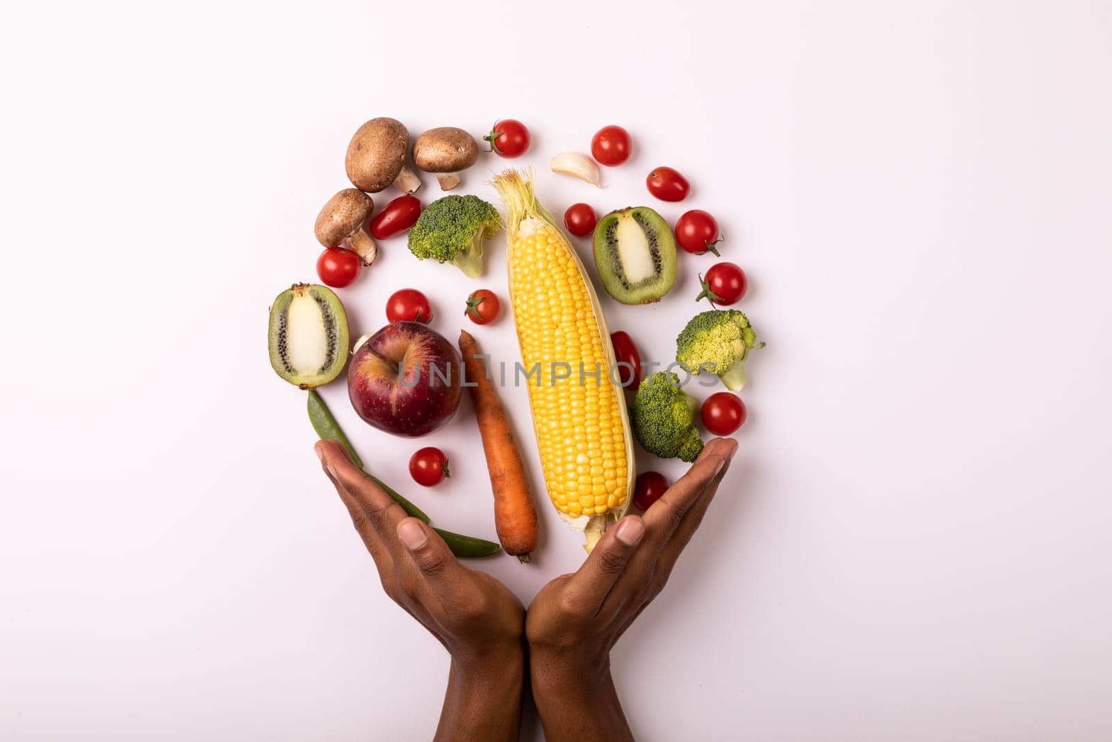 Cropped hands by vegetables and fruits arranged in circle by copy space on white background. unaltered, food, healthy eating, organic concept.