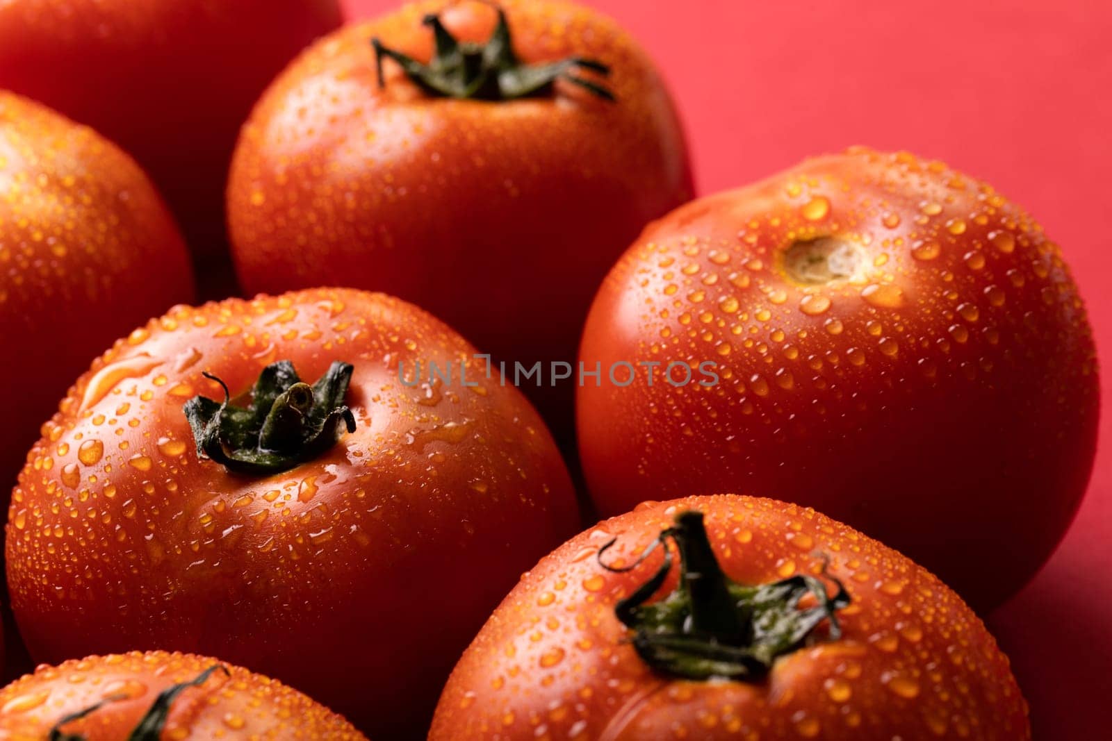 Close-up of fresh red tomatoes with water drops over colored background. unaltered, food, healthy eating, organic concept.