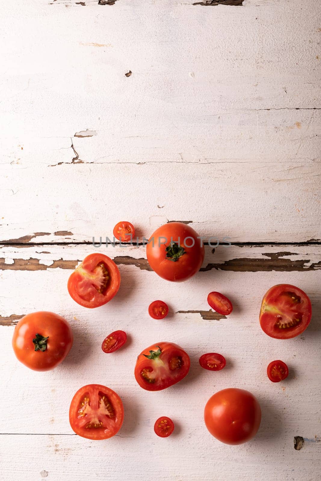 Directly view of fresh tomato variations on white wooden table by Wavebreakmedia