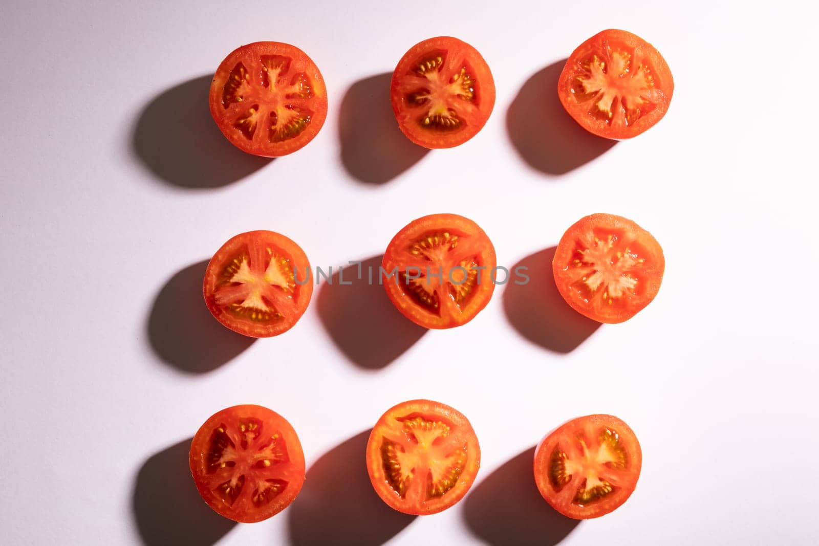 Directly above view of fresh red tomato halves arranged in a row on white background by Wavebreakmedia