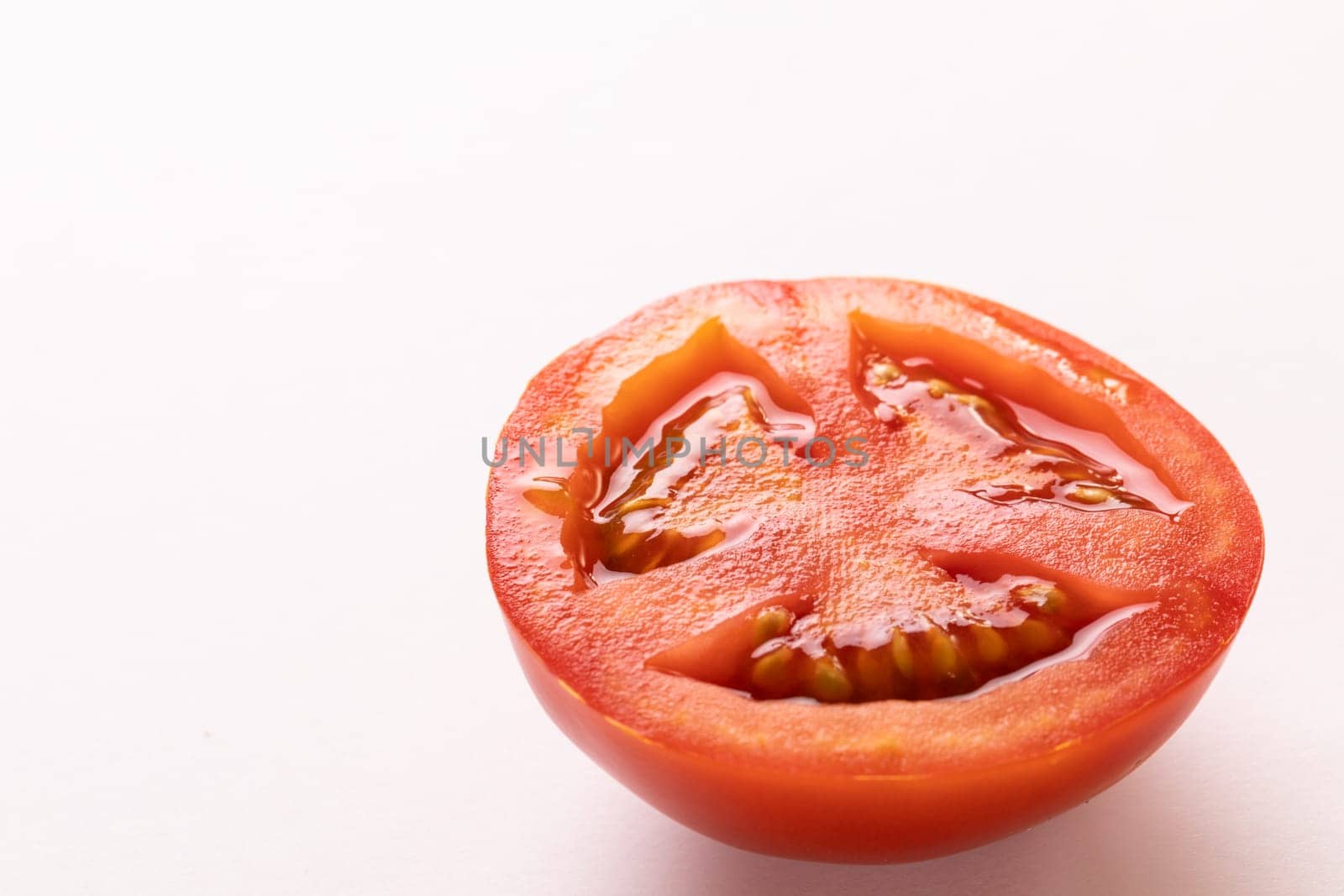Close-up of fresh single red tomato half by copy space on white background. unaltered, food, healthy eating, organic concept.