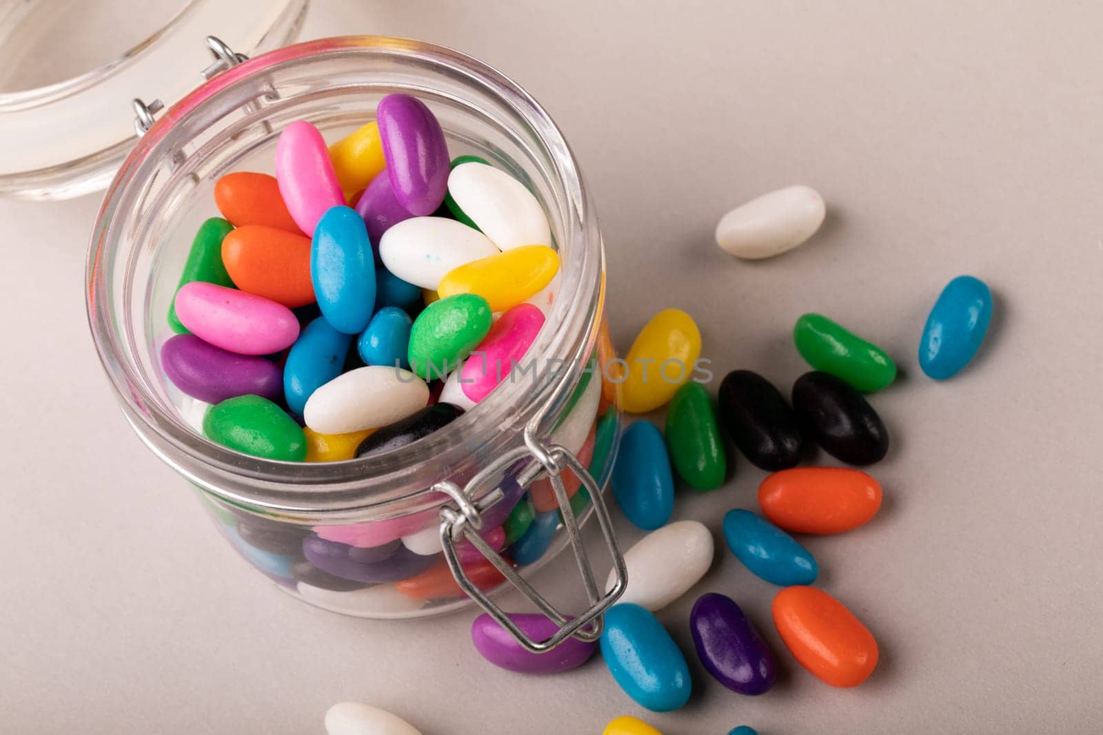 High angle view of colorful candies with open glass jar on white background. unaltered, sweet food and unhealthy eating concept.