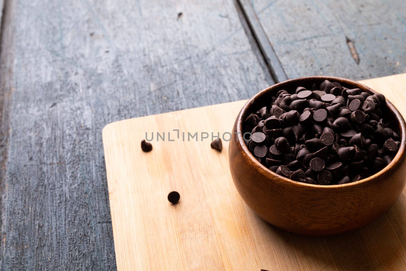 High angle view of chocolate chips in bowl on cutting board over wooden table by Wavebreakmedia
