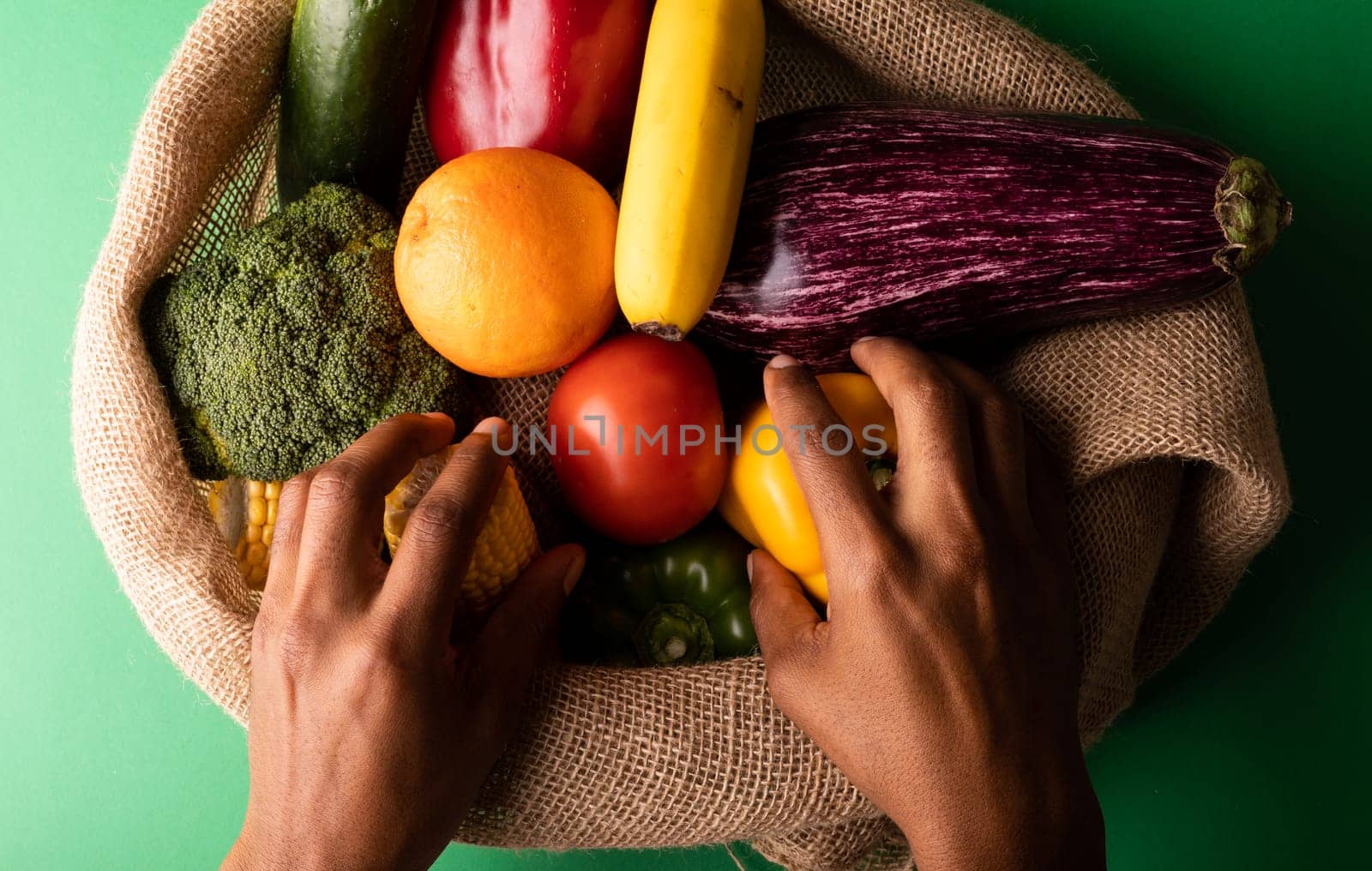 Cropped hands of mixed race man picking up vegetables from burlap sack by Wavebreakmedia