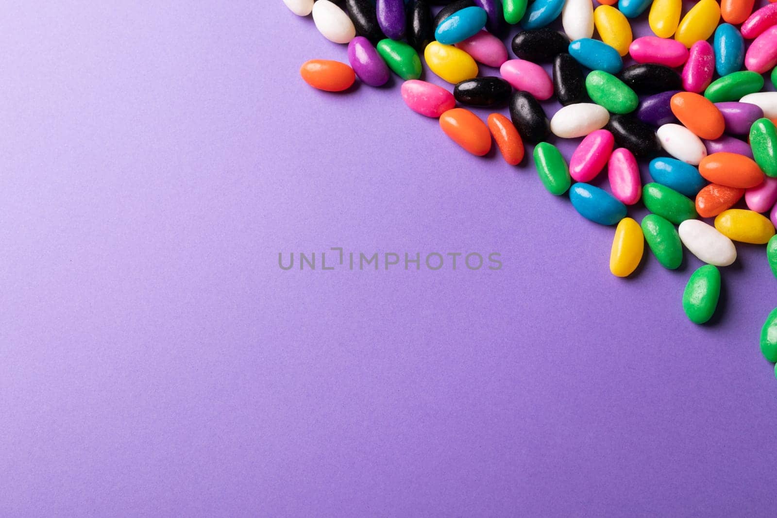 Directly above view of multi colored candies on purple background with copy space. unaltered, sweet food and unhealthy eating concept.