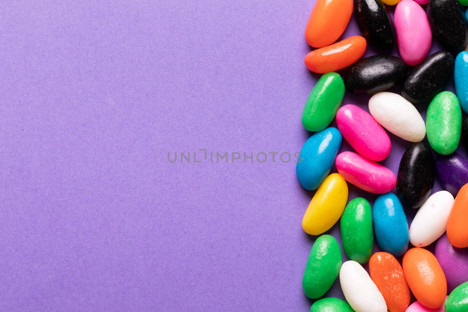 Overhead view of sweet multi colored candies by copy space on purple background by Wavebreakmedia